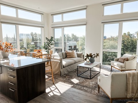 a living room with couches and chairs and large windows